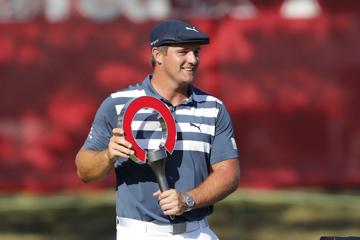 Bryson DeChambeau holds the Rocket Mortgage Classic golf tournament trophy Sunday, July 5, 2020, at Detroit Golf Club in Detroit. DeChambeau won the tournament by three strokes for his first victory of the season and sixth overall. (AP Photo/Carlos Osorio)
