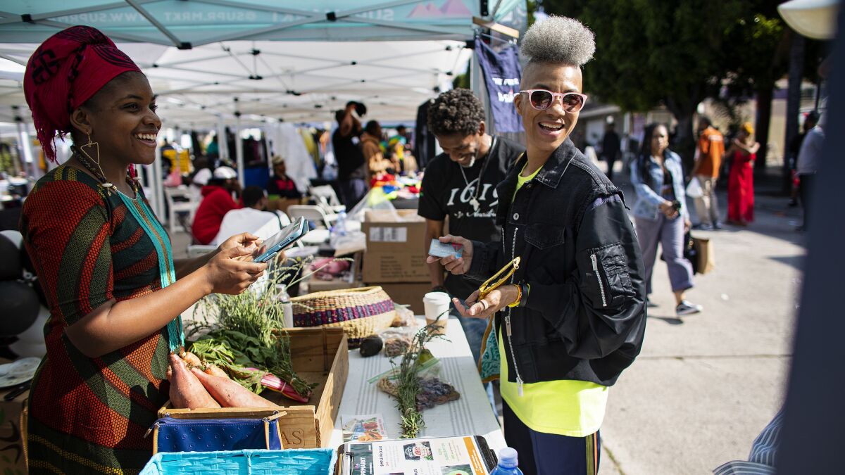 Olympia Auset, left, owner and founder of Süprmarkt, sells groceries to customers in Leimert Park Village on June 15, 2019.