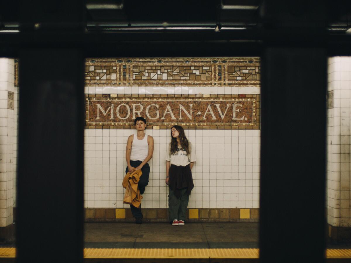 Two friends wait for the subway on a NYC platform.