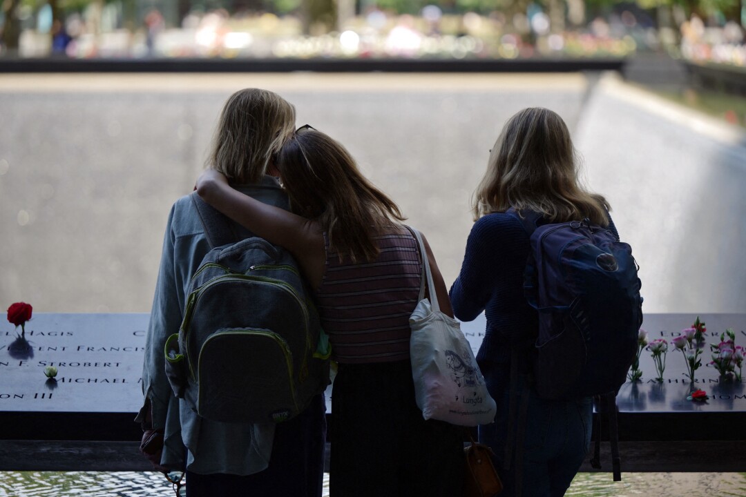 Trois personnes se tiennent ensemble au mémorial et musée national du 11 septembre