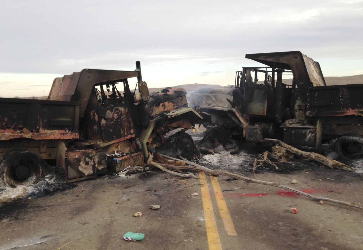 The burned hulks of heavy trucks sit on Highway 1806 near Cannon Ball, N.D., on Friday, near the spot where protesters of the Dakota Access pipeline were evicted from private property a day earlier.