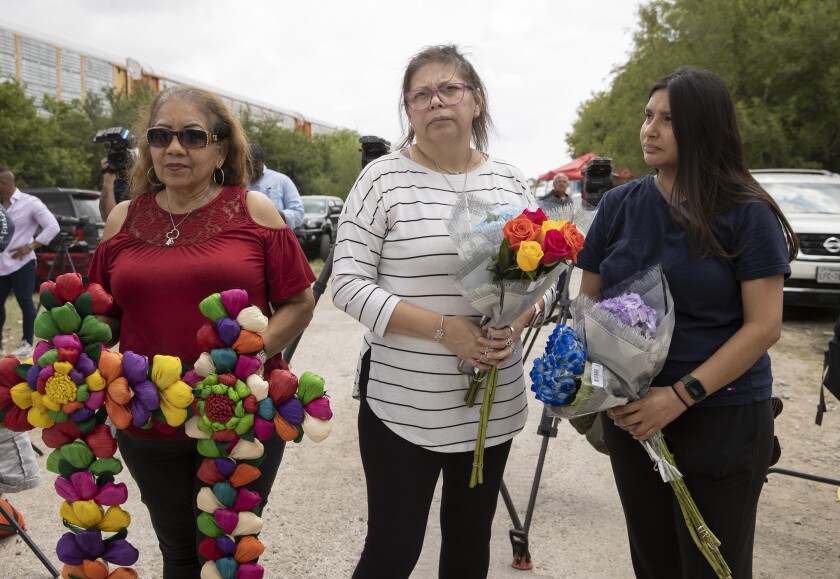 Angelita Olvera, left to right, Marissa Hernandez, and her daughter Delilah Hernandez, pay their respects at the scene on Quintana Road, Tuesday, June 28, 2022, in San Antonio, where officials say dozens of people have been found dead and multiple others were taken to hospitals with heat-related illnesses after a semitrailer containing suspected migrants was found. (Jay Janner/Austin American-Statesman via AP)