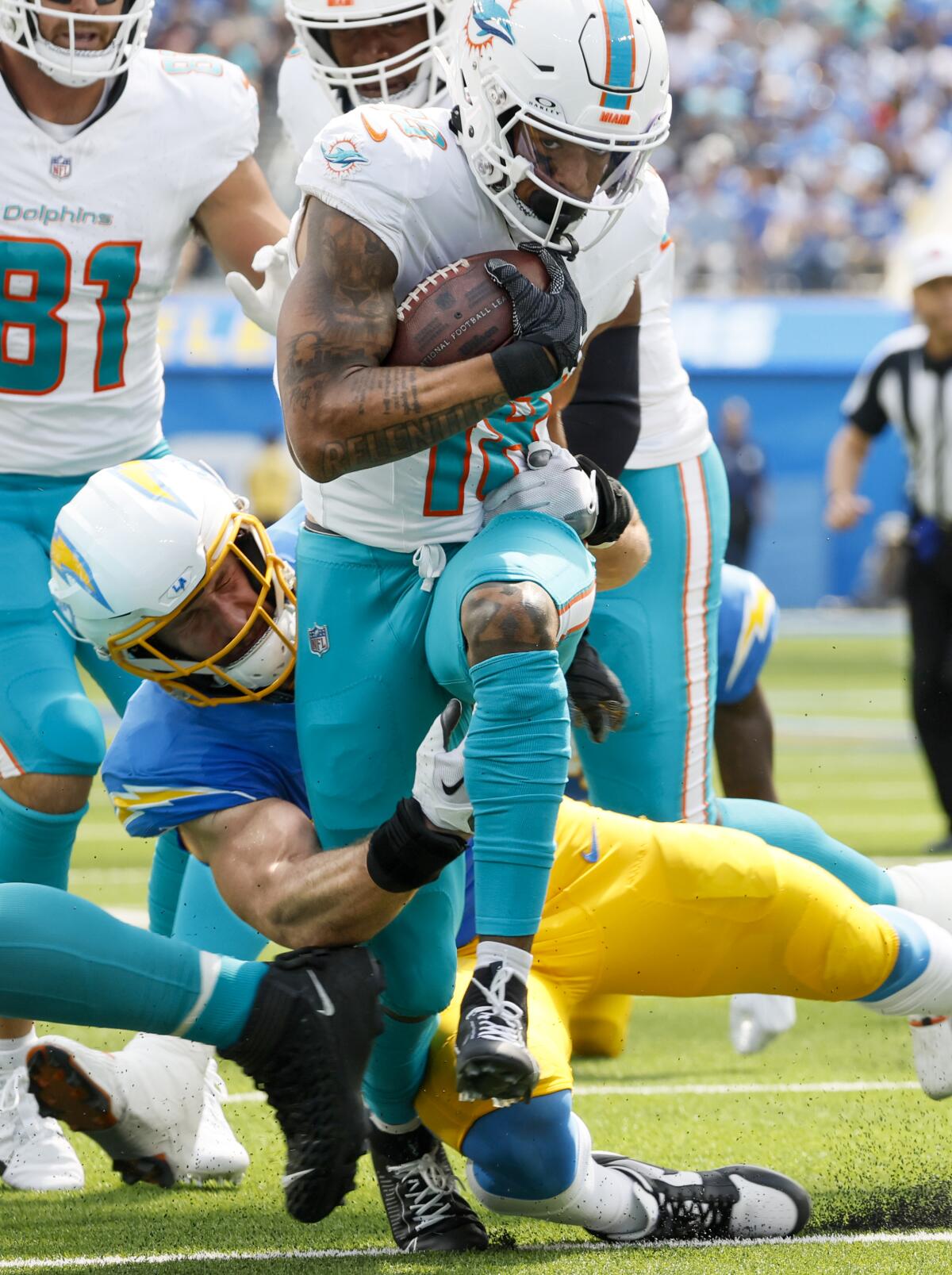 Dolphins wide receiver Erik Ezukanma (18) runs through the tackle of Chargers linebacker Joey Bosa.