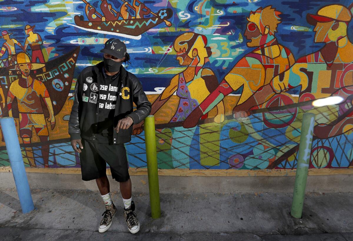 ShowzArt with the mural "The Living Water," to which he contributed, near the corner of Fifth Street and Central Avenue in L.A.