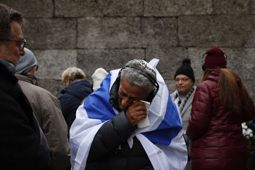Zvika Karavany, 72, a Yemeni-born Israeli, wipes his tears in front of the Death Wall in the former Nazi German concentration and extermination camp Auschwitz during ceremonies marking the 78th anniversary of the liberation of the camp in Oswiecim, Poland, Friday, Jan. 27, 2023. (AP Photo/Michal Dyjuk)
