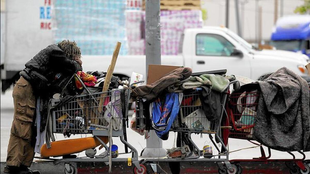 A homeless man pushes a train of shopping carts near 9th Street in L.A.'s skid row.