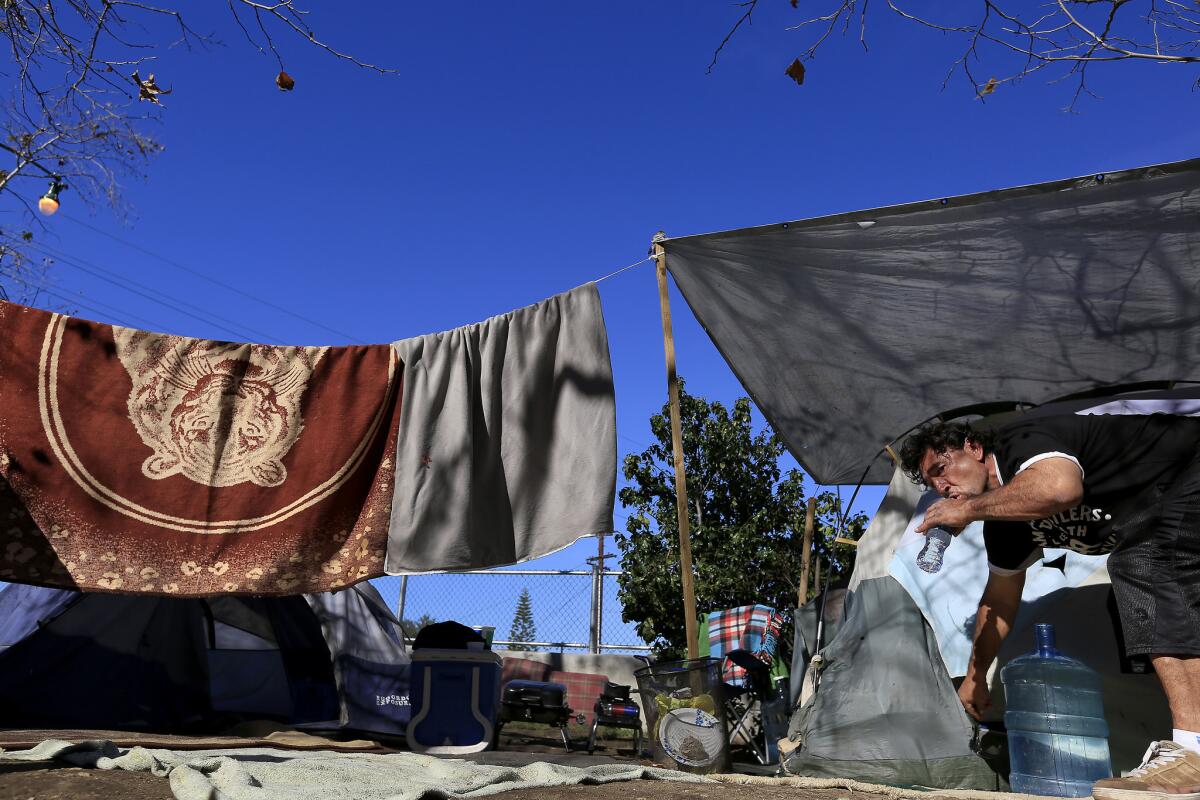 Miguel Hernandez, 50, drinks water outside the tent where he lives along the Arroyo Seco and the Pasadena Freeway in January.