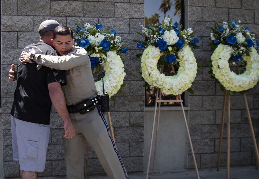 CHP officers embrace at a memorial 