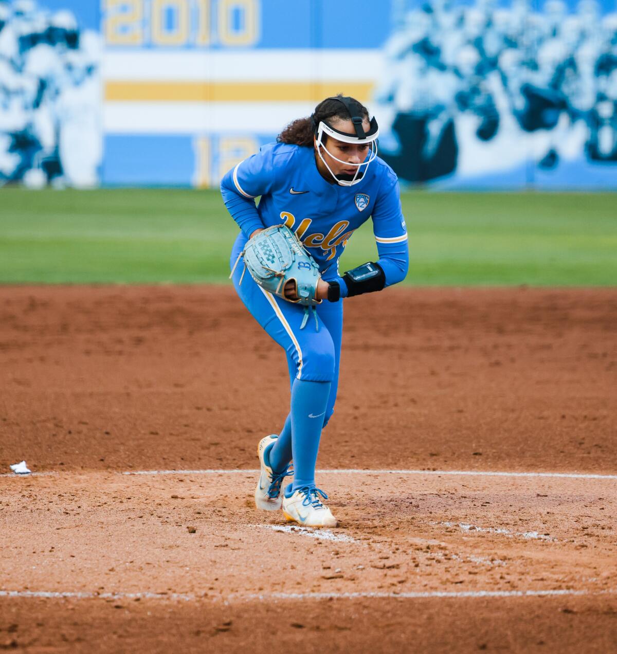 UCLA right-hander Taylor Tinsley ends up in the pitching circle in a face mask and blue uniform