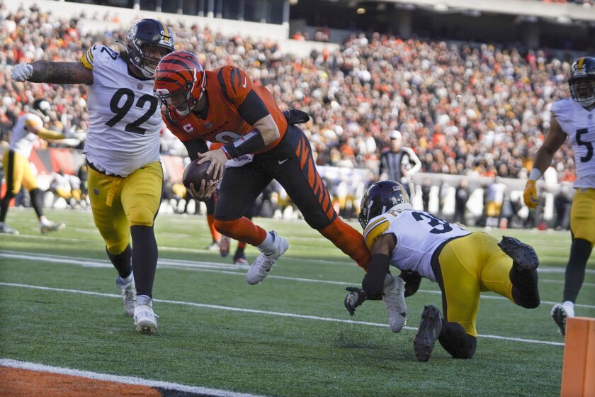 El quarterback de los Bengals de Cincinnati Joe Burrow corre entre el safety Minkah Fitzpatrick y el defensive end Isaiahh Loudermilk de los Steelers de Pittsburgh para anotar en el encuentro del domingo 28 de noviembre del 2021. (AP Photo/Jeff Dean)