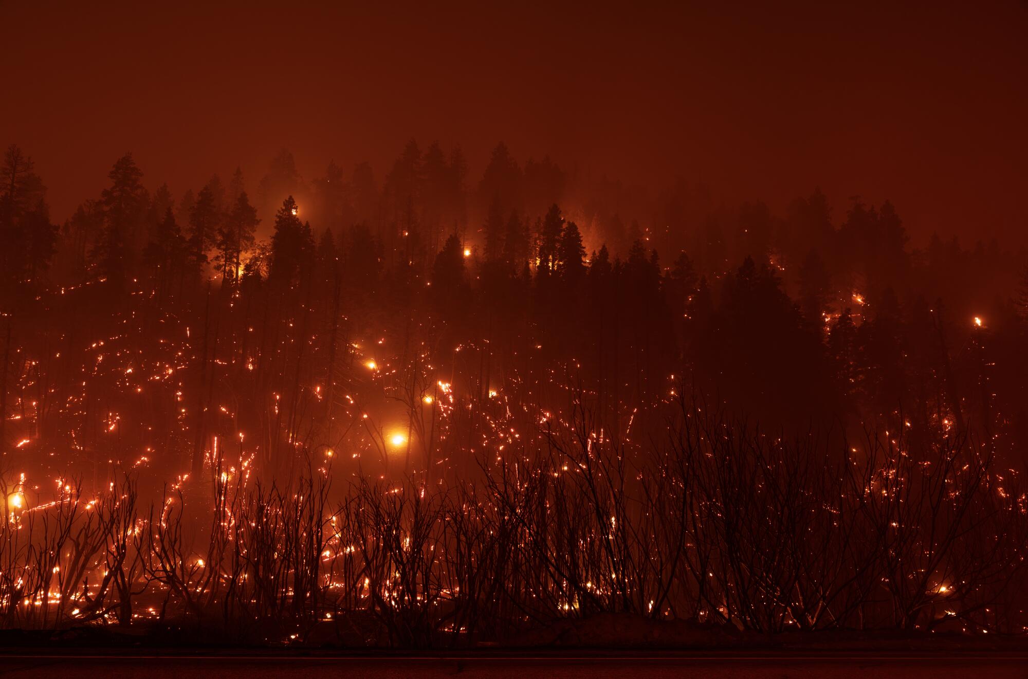 Burning embers twinkle on a mountain ridge at night.