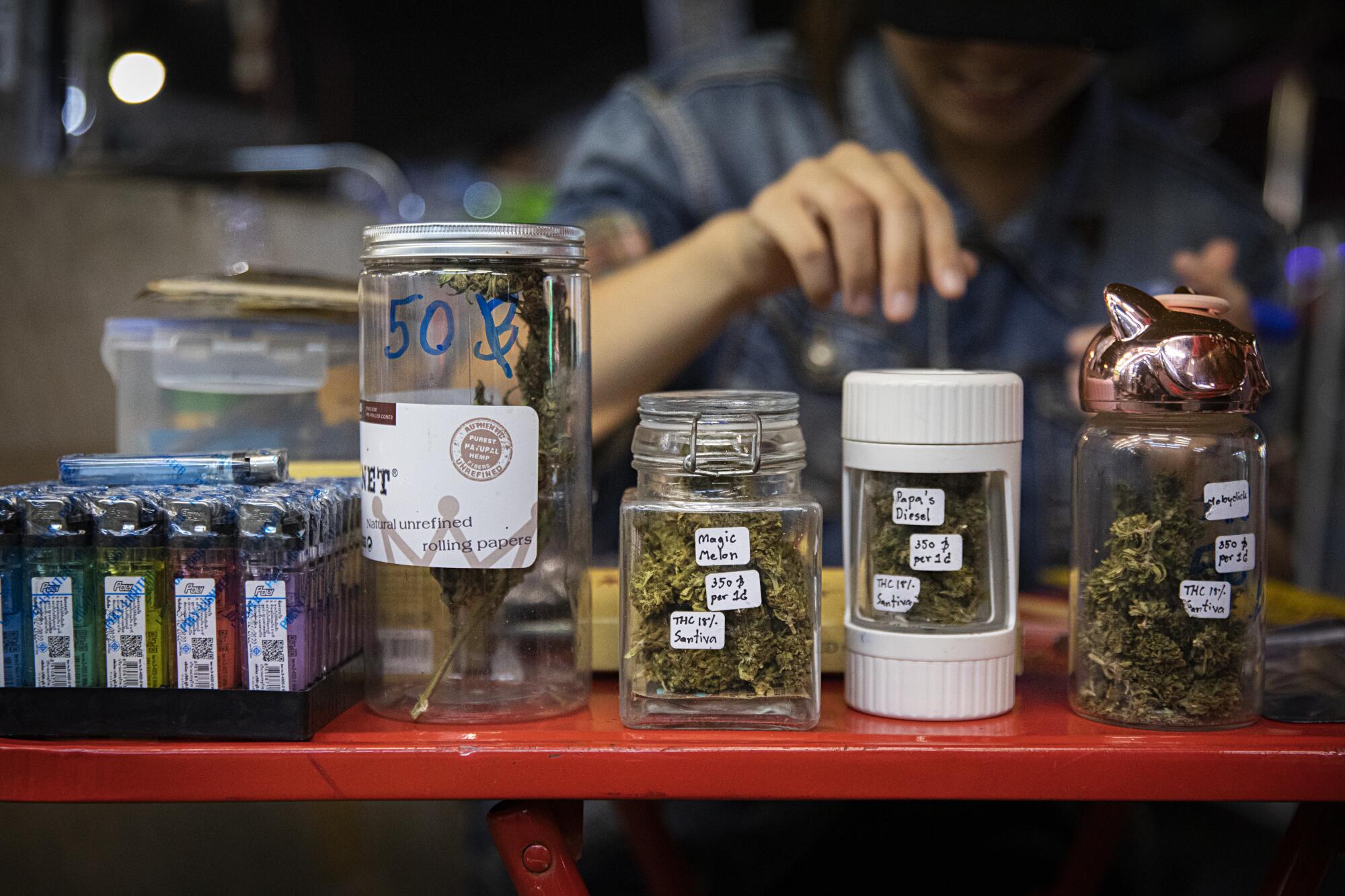 The owner of a marijuana stand in Bangkok prepares a joint for tourists.
