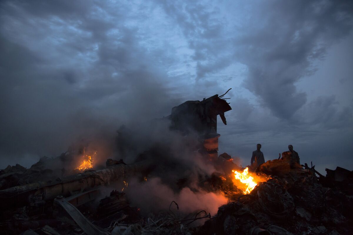 People walk amid the debris of Malaysia Airlines Flight 17 near the village of Hrabove in eastern Ukraine on July 17, the day the jet was shot down.