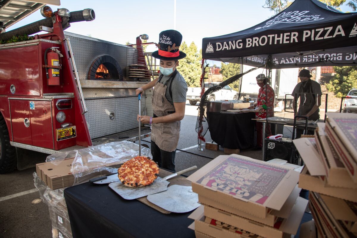 Russell Carrilo pulls a finished pizza from the Dang Brother Pizza fire truck