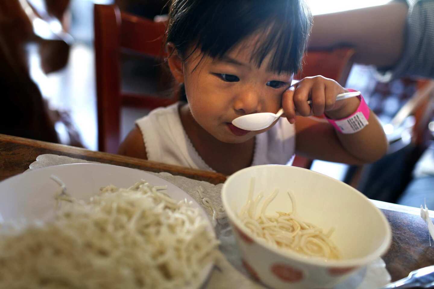 Quan Vy Da restaurant in Westminster specializes in cuisine from the central Vietnam area. Savannah Hoang, 2, of Westminster, scoops some noodles into her mouth during lunch.