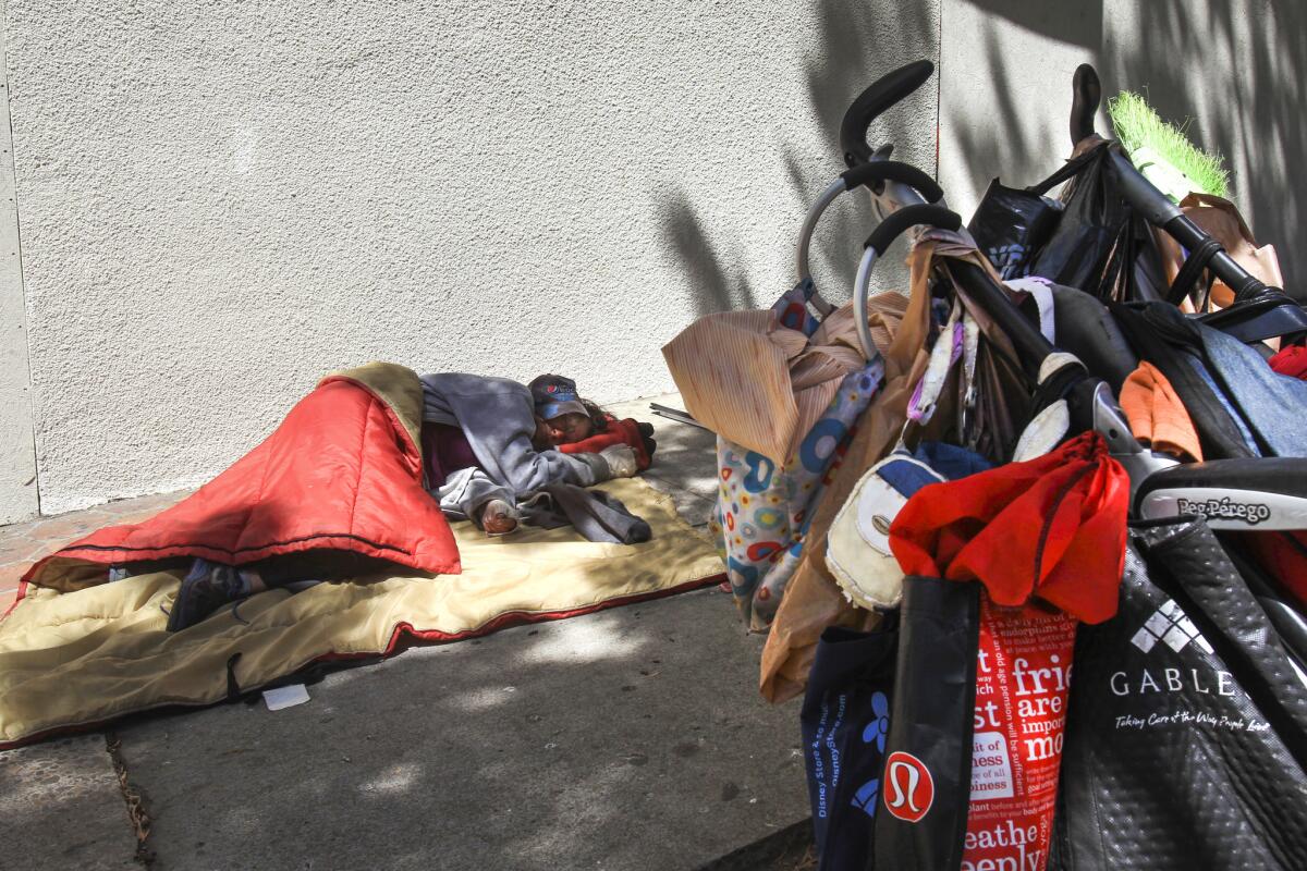 A homeless woman sleep on the sidewalk next to her cart of her belongings on the sidewalk on A Street in San Diego in 2017.