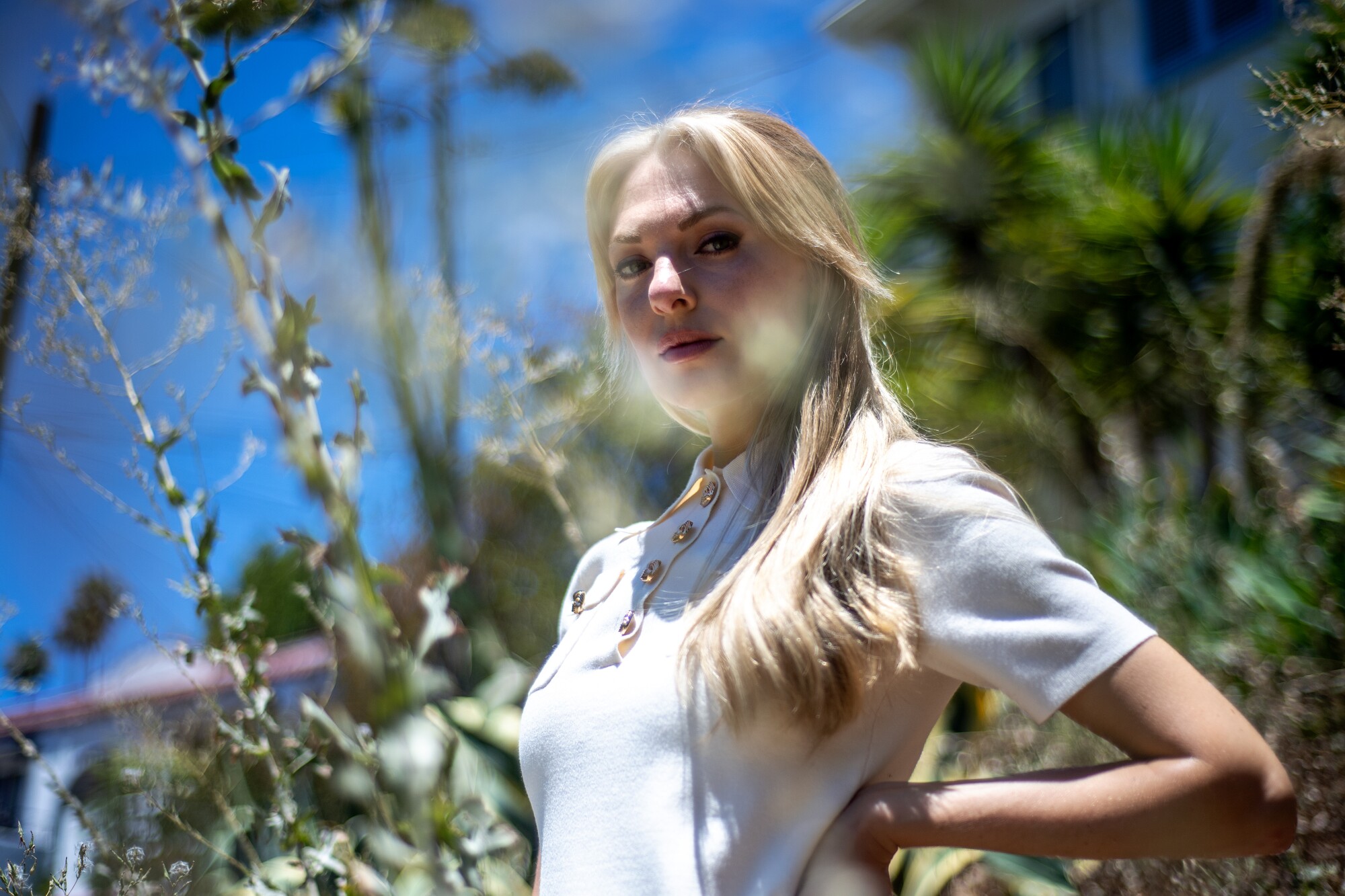  A blond woman in a white dress gazes into the camera.