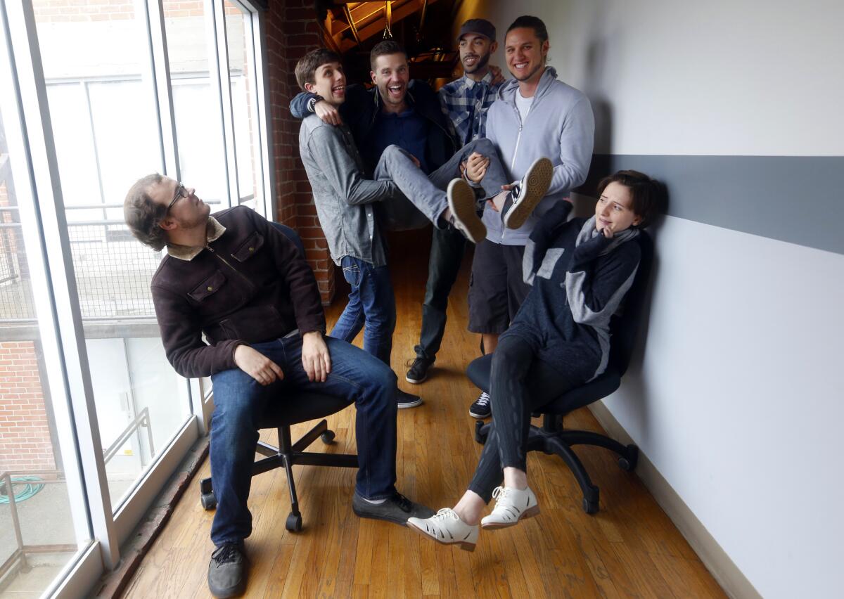 Lead programmer Bryant Cannon, left, designer Kevin Riach (holding up Sean Krankel, CEO), Creative Director Adam Hines, designer Spencer Stuard and lead artist Heather Gross are all part of the team behind Night School Studios.