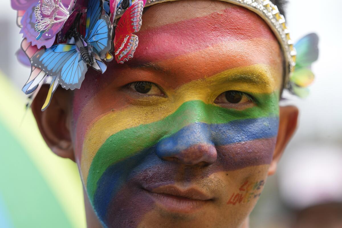 A participant with rainbow color face paint and butterflies as accessories takes part in the Pride Parade in Bangkok.