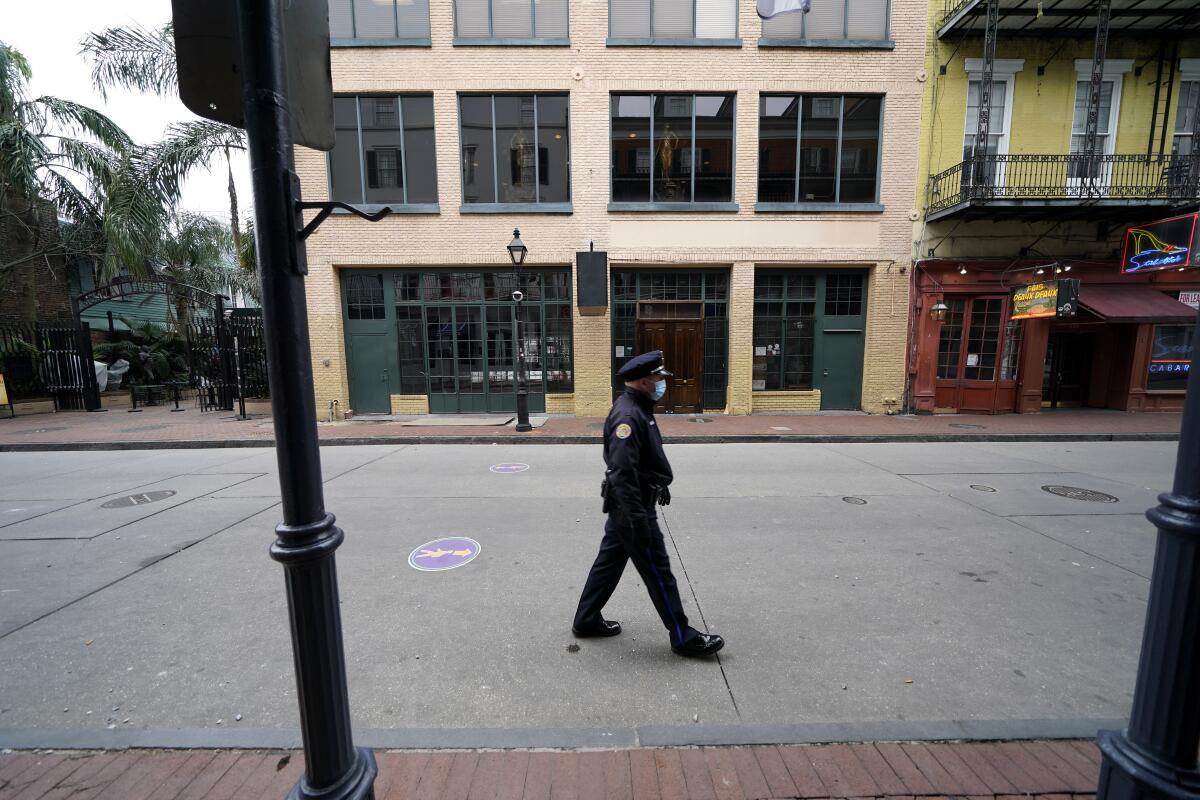 A police officer walks down a nearly deserted Bourbon Street. 