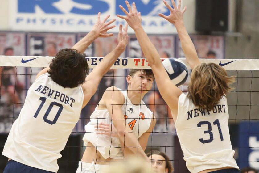Noah Robin of Huntington Beach (24) hits the ball into the arms of defense in Newport Harbor’s Caden Garrido (10) and Dane Carroll (31) during the Tesoro Tournament in volleyball on Monday.