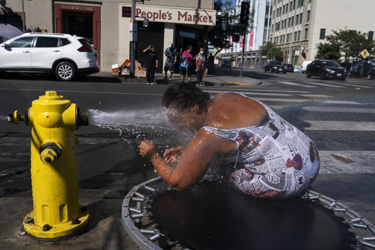 A woman leans into a stream of water from a fire hydrant