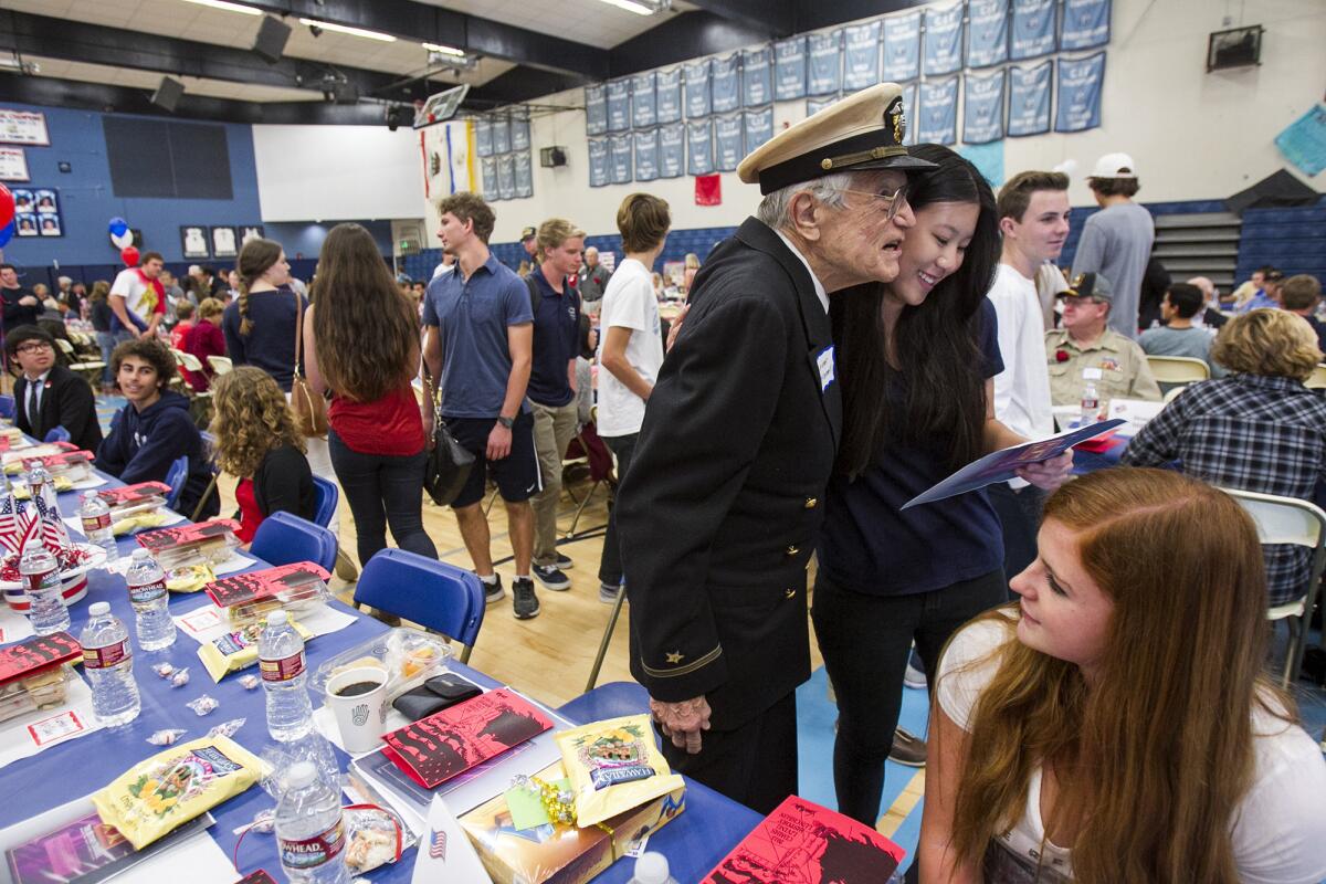 Jayme Chow, 15, gets a hug from Lorimer McConnell, 89, a US Navy photographer who served in World War II, during the Living History Luncheon at Corona del Mar High School on Thursday