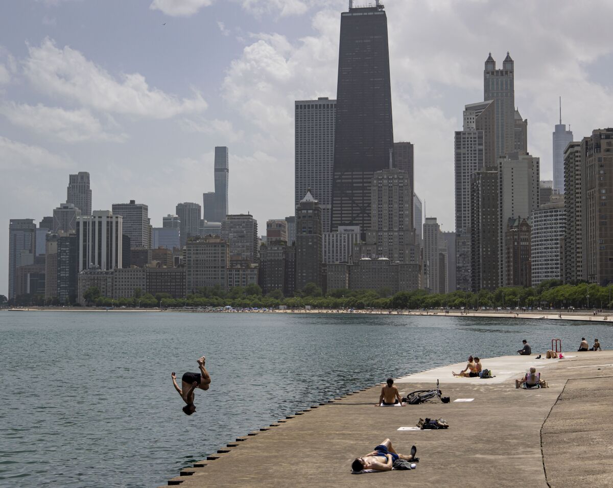 A man leaps into Lake Michigan along the lakefront near Oak Street Beach while sunbathers soak up temperatures in the 90s on Wednesday, June 15, 2022, in Chicago. (Brian Cassella/Chicago Tribune via AP)