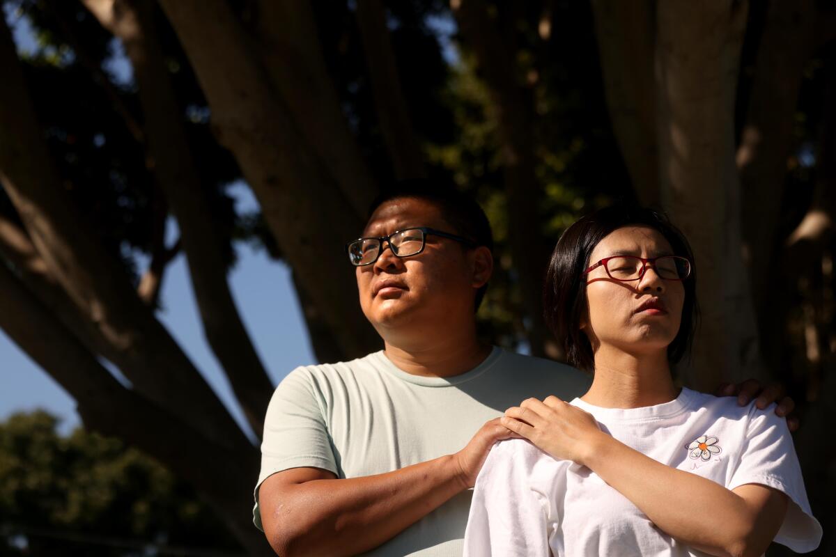 Tingbo Cao, left, and wife Qilian Zhou together under the shade of a tree