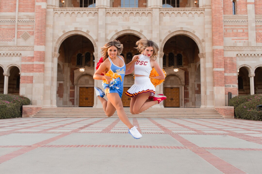 USC Song Girls captain Hannah Shaw, right, and her cousin, UCLA dance team member Lauren Shaw, jump in the air