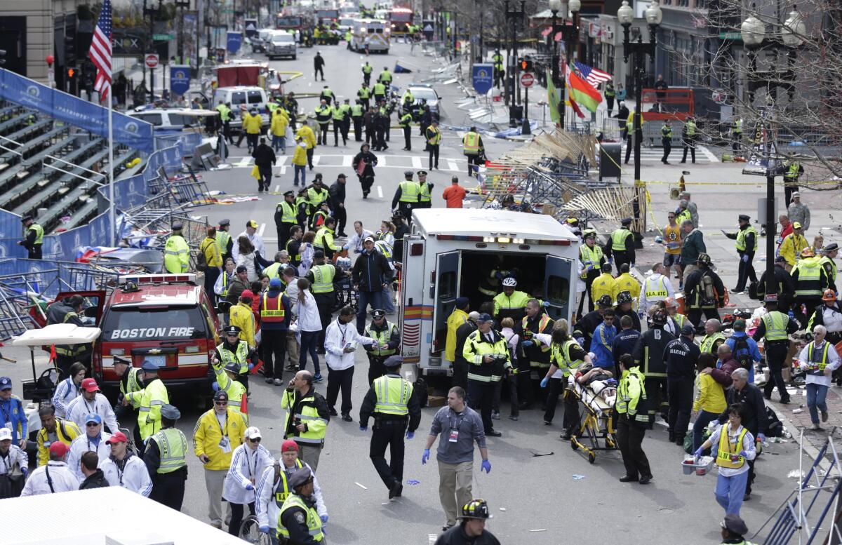 FILE— In this Monday April 15, 2013 file photograph, emergency workers aid injured people at the finish line of the 2013 Boston Marathon following two explosions in Boston. Mass. Boston is marking eight years since the bombing at the 2013 Boston Marathon killed three people and injured scores of others. Acting Mayor Kim Janey on Thursday, April 15, 2021, paid a noontime visit to the downtown memorial marking the bombing site. (AP Photo/Charles Krupa, File)