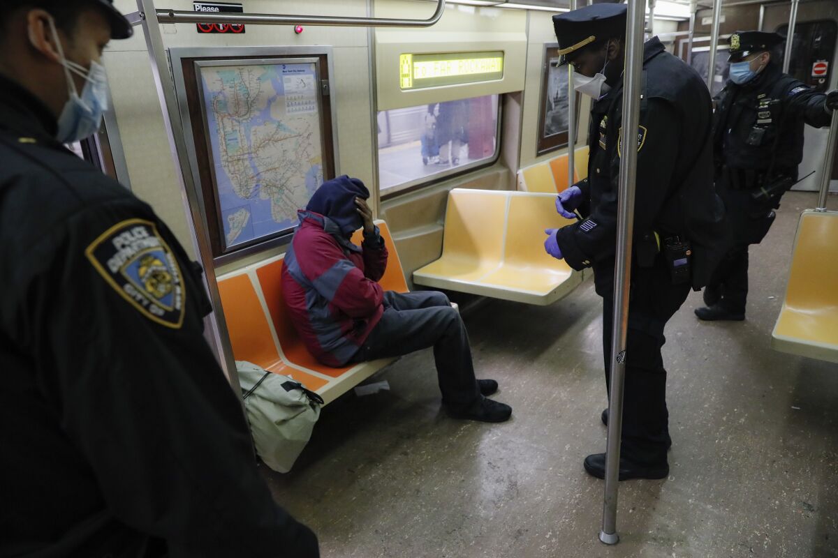 New York Police officers wake up a sleeping passenger on the subway. 
