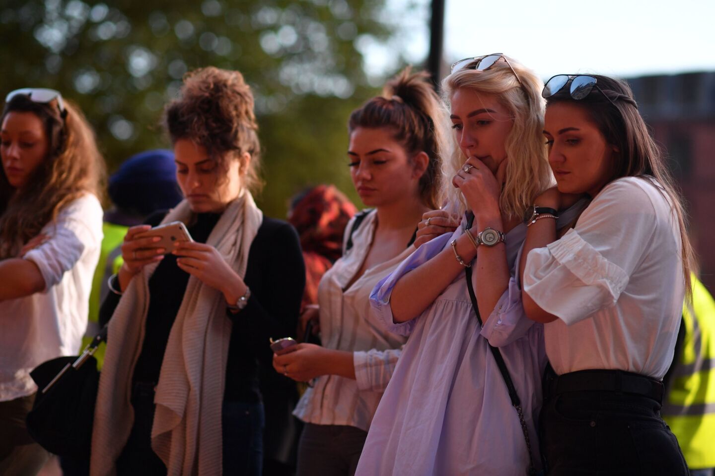 People pause in front of candles set up in Albert Square in Manchester, England.