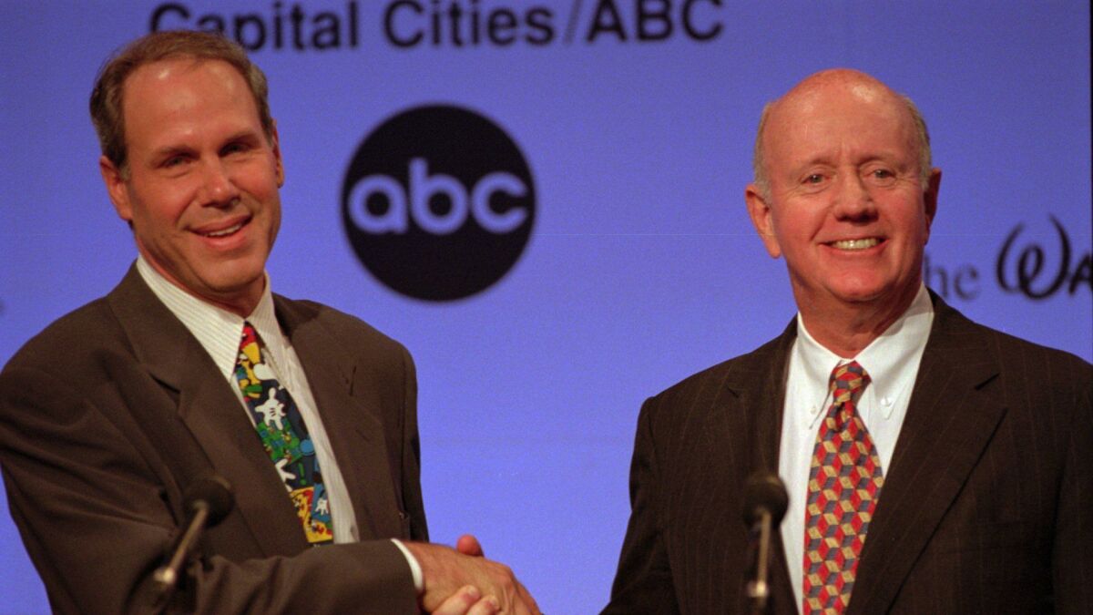 Then-Disney Chairman Michael Eisner, left, shakes hands with Capital Cities/ABC Chairman Thomas Murphy in 1996.