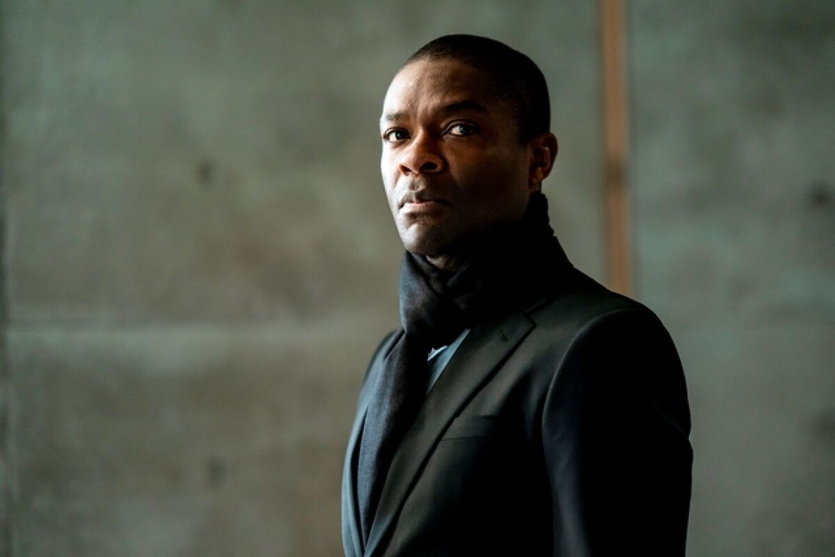 A man in a black coat stares into the distance.