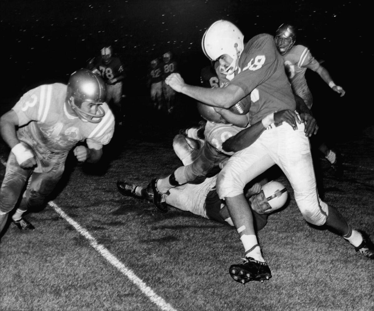 Roman Gabriel, North Carolina State quarterback, is in the clutches of one UCLA player.