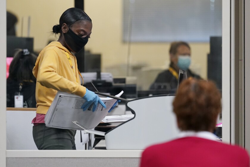 A county election worker scans mail-in ballots