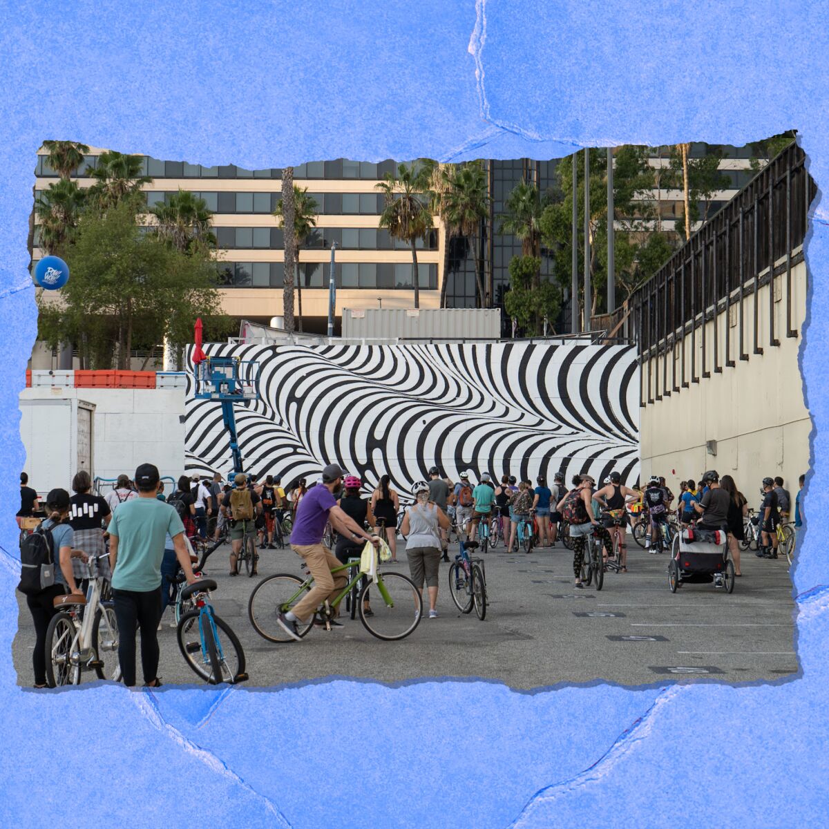 People on bikes stand in front of a large wall mural of undulating black and white lines.