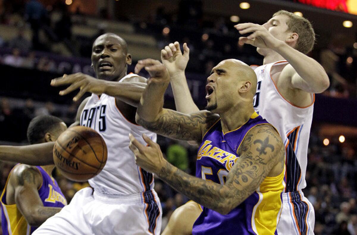 Lakers center Robert Sacre battles Bobcats big men Bismack Biyombo, left, and Cody Zeller for a rebound during a game earlier this season in Charlotte, N.C.