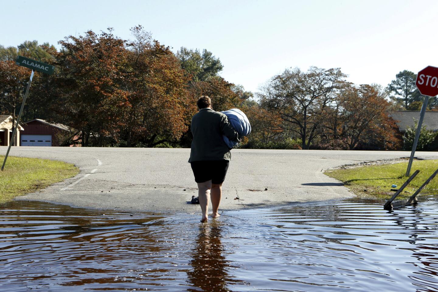 Janet Meier makes her way out of the floodwaters associated with Hurricane Matthew surrounding her home after retrieving a warm blanket and her laptop computer on Oct. 13, 2016 in Lumberton, N.C.