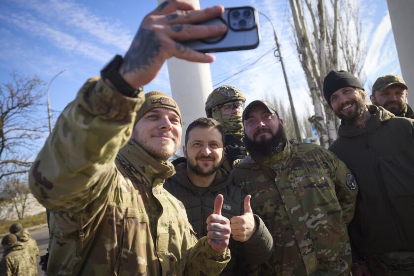 In this photo provided by the Ukrainian Presidential Press Office and posted on Facebook, Ukrainian soldiers take a selfie with President Volodymyr Zelenskyy, centre, during his visit to Kherson, Ukraine, Monday, Nov. 14, 2022. Ukraine's retaking of Kherson was a significant setback for the Kremlin and it came some six weeks after Russian President Vladimir Putin annexed the Kherson region and three other provinces in southern and eastern Ukraine — in breach of international law — and declared them Russian territory. (Ukrainian Presidential Press Office via AP)