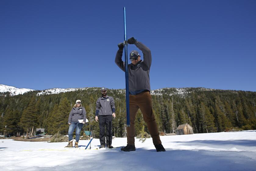 Sean de Guzman, chief of snow surveys for the California Department of Water Resources, right, plunges the snow survey tube into the snow pack as DWR's Chief of State Water Project Operations Molly White, left and Water Resources Engineer Nathan Burley, center look on during the third snow survey of the season at Phillips Station near Echo Summit, Calif., Thursday, Feb. 27, 2020. The survey found the snowpack at 29 inches deep with a water content of 11.5 inches at this location. (AP Photo/Rich Pedroncelli)