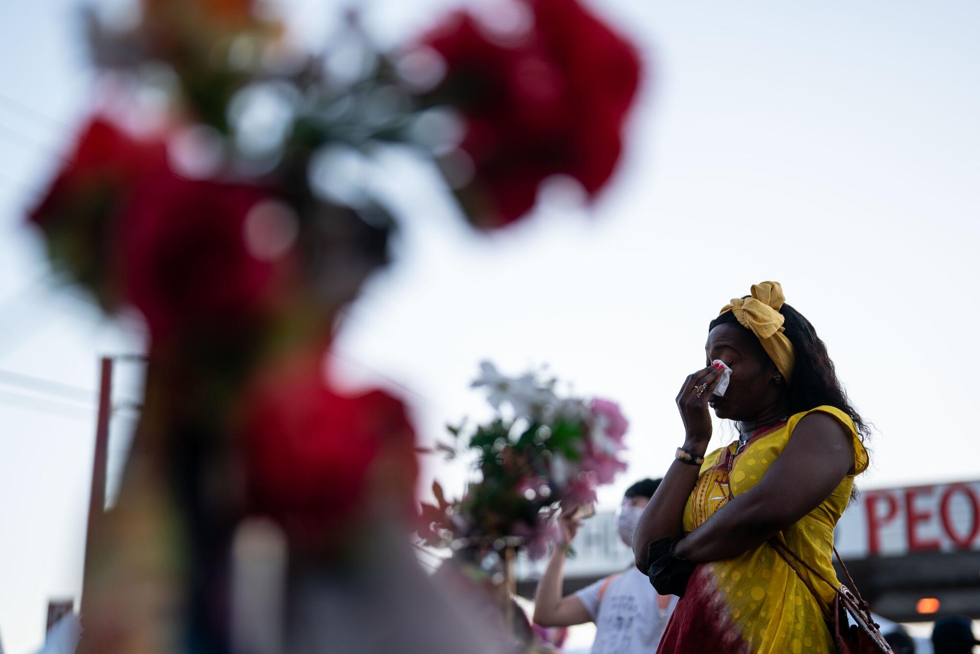 A woman wipes her eyes while visiting a memorial.