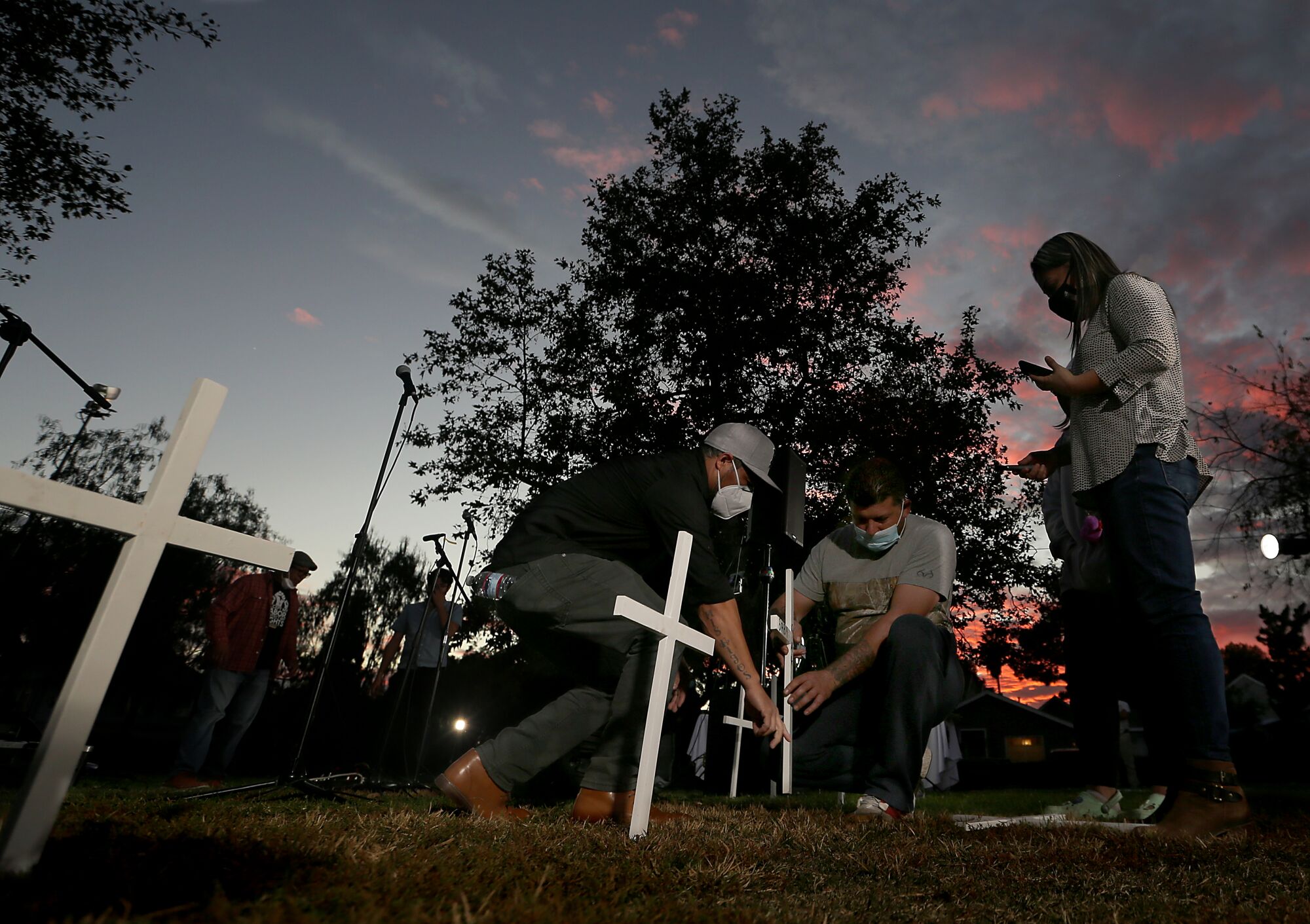Residents plant white crosses into the ground