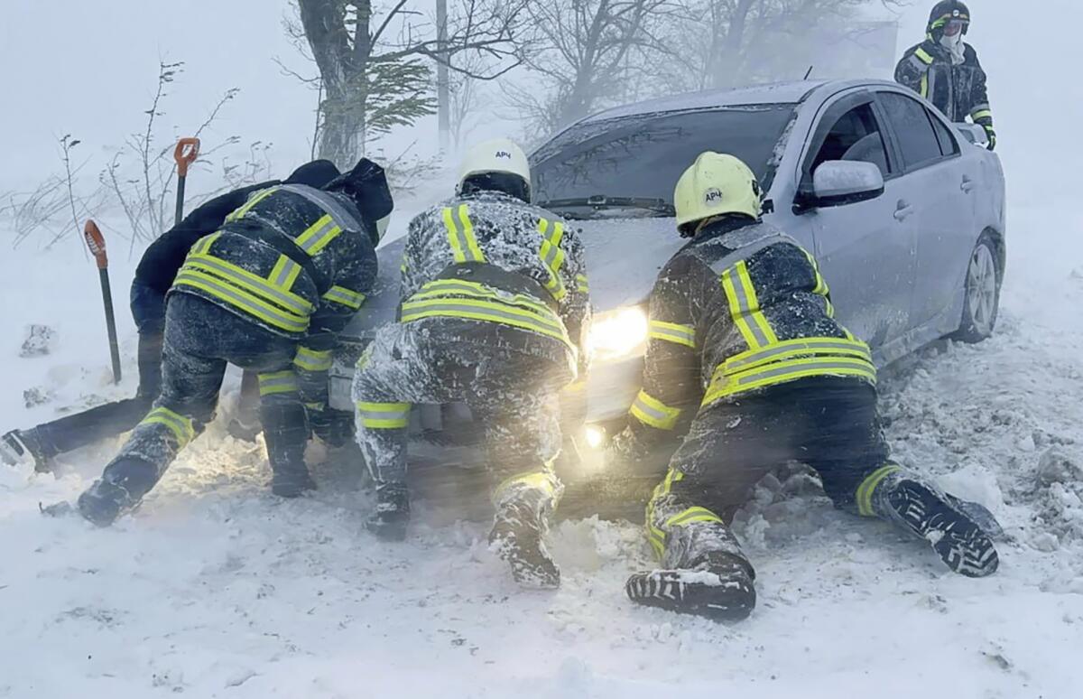 Ukrainian emergency workers trying to push a car trapped in snow