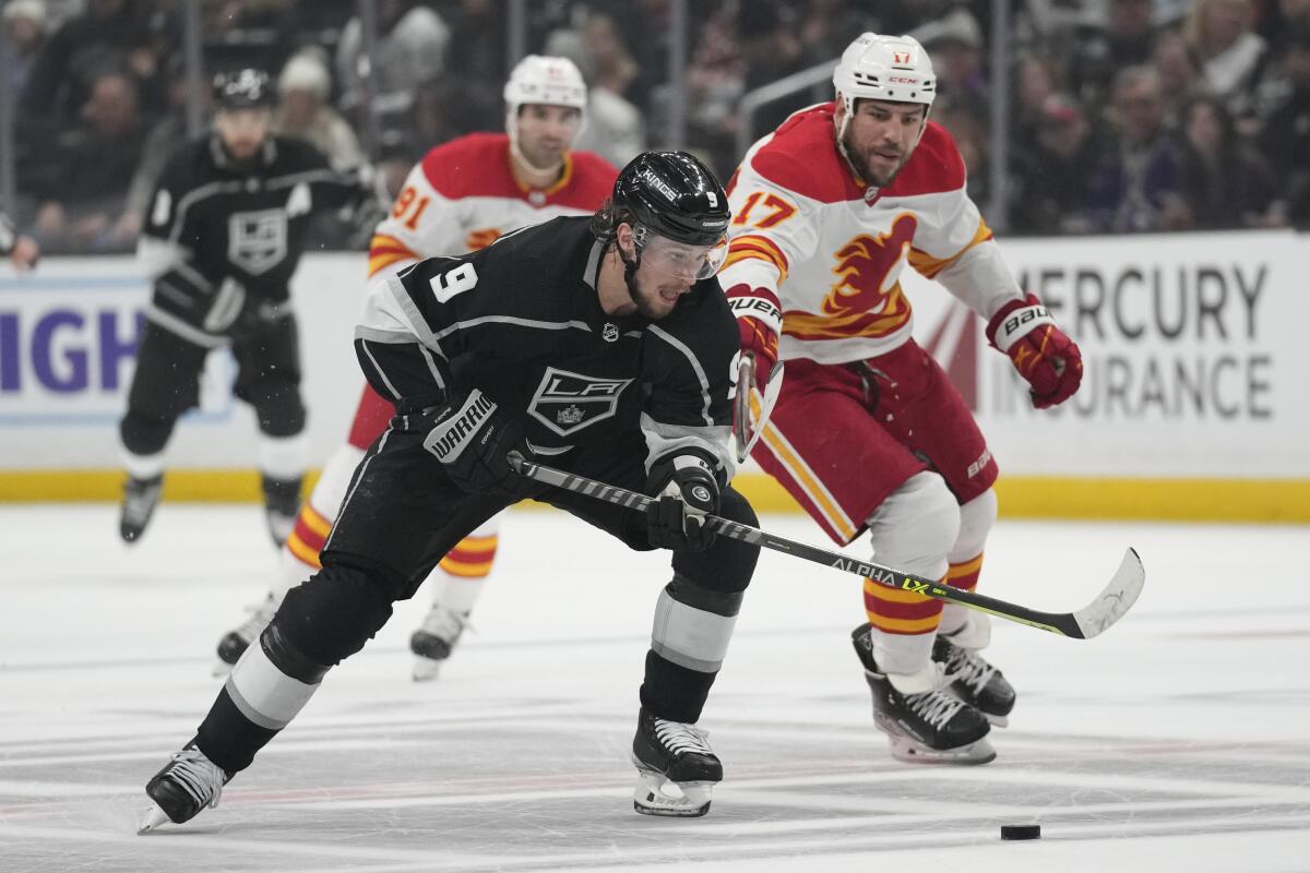 Kings forward Adrian Kempe, left, controls the puck in front of Calgary Flames forward Milan Lucic.