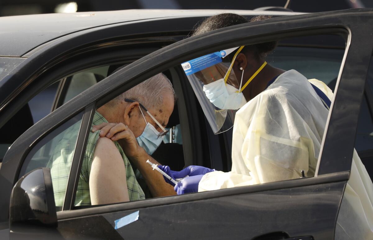 Staff and volunteers distribute the COVID-19 vaccine to people as they remain in their vehicles at the Forum in Inglewood.