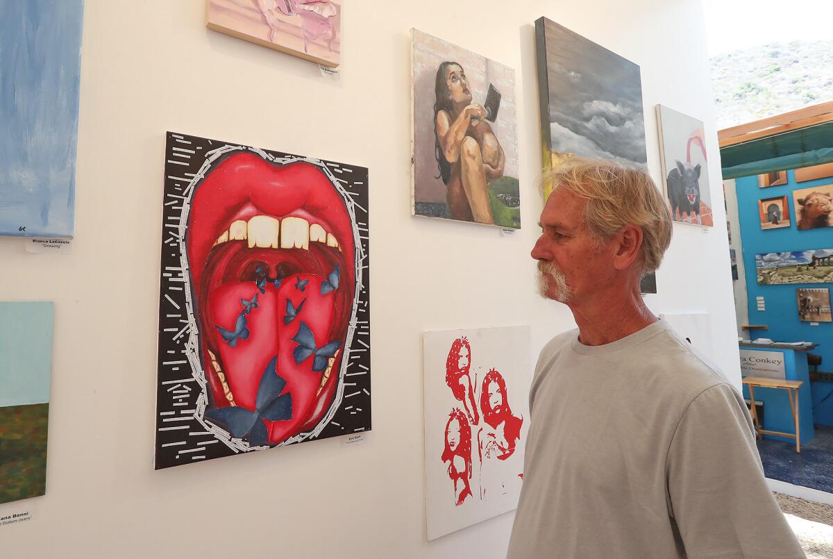 Bud Weir, a local artist and exhibitor, stands in the Laguna Beach High School Art Spot next to a piece by Zoe Gort.