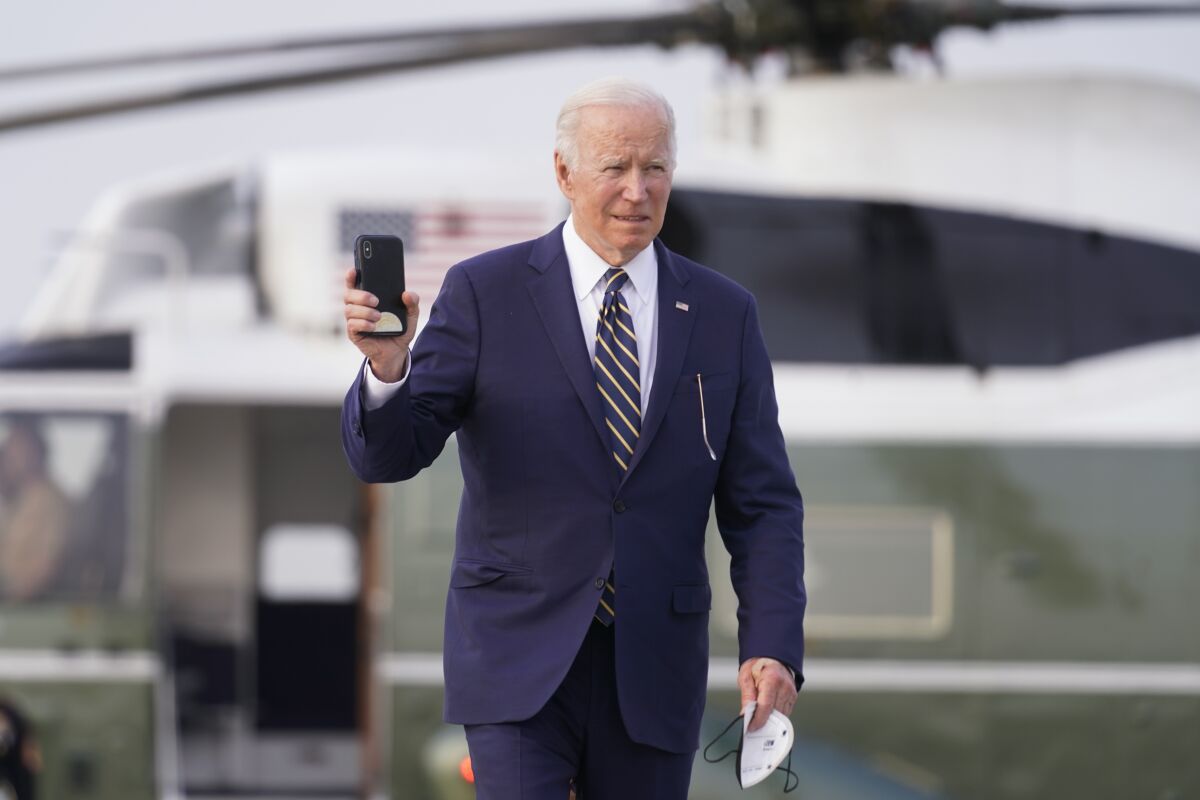 President Joe Biden holds a cell phone as he walks to board Air Force One at Chicago O'Hare International Airport, Wednesday, May 11, 2022, in Chicago. (AP Photo/Andrew Harnik)