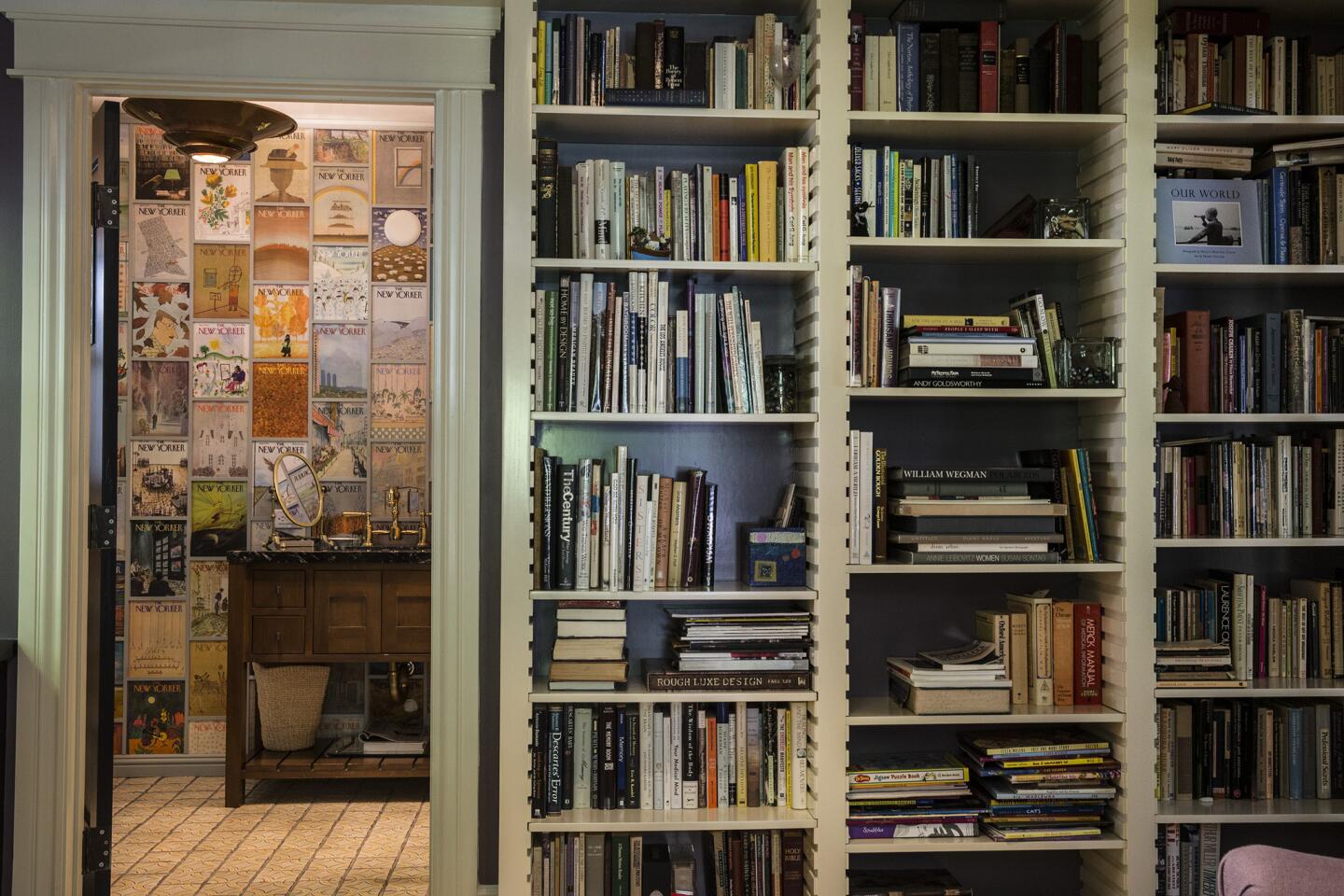 Custom bookshelves line the walls of Linda Hunt and Karen Klein's library. The bathroom to the left is lined with vintage New Yorker covers from Hunt's collection.